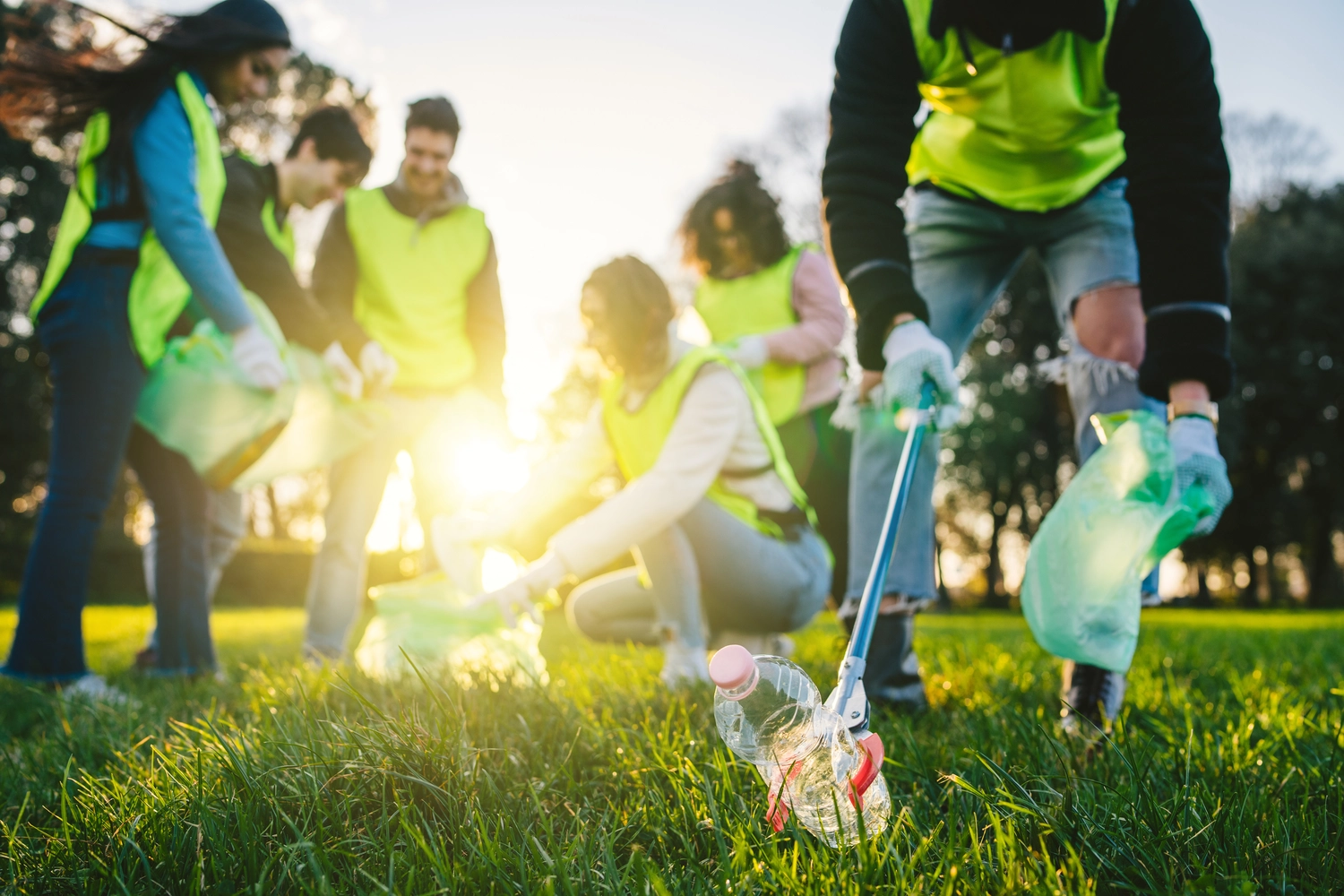 Odenwald - Stiftung Naturschutz - barrierefrei - Gruppe von Freunden während einer ehrenamtlichen Müllsammelaktion in einem Park bei Sonnenuntergang
